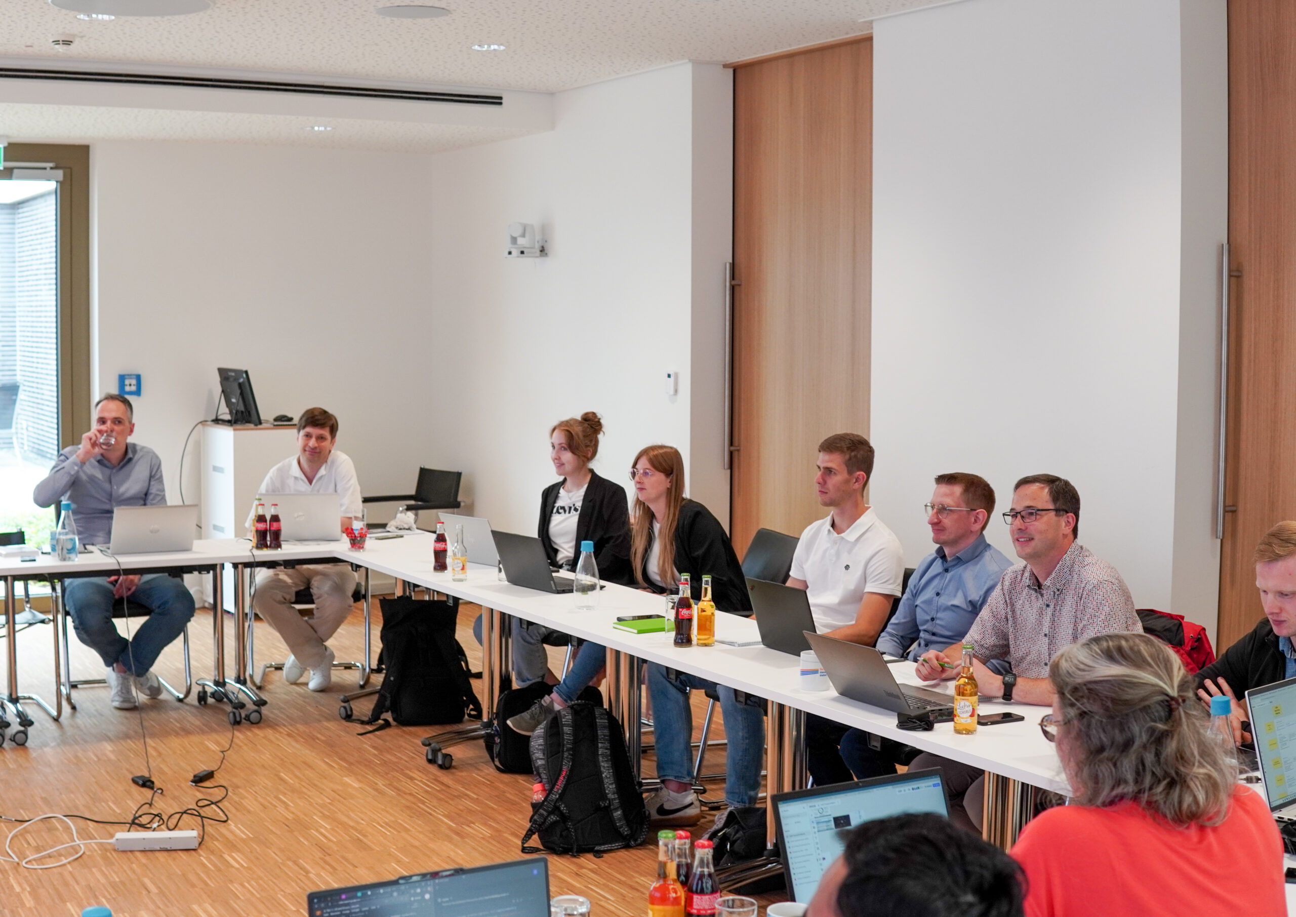 Bild Workshop Halbjahresbilanz, Projektteilnehmer sitzen an einem u-förmigen Tisch und arbeiten am Projektstatus weiter